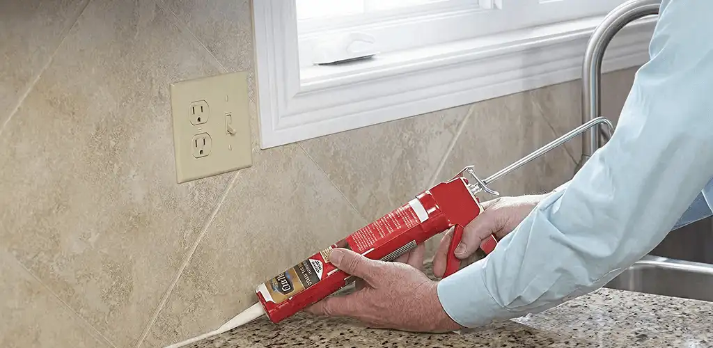 Handyman applying caulk along a kitchen backsplash and countertop seam in Clearwater, FL