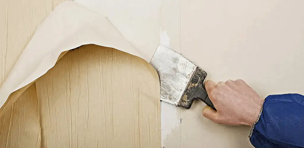 Handyman removing wallpaper with a scraper for wall preparation in Clearwater, FL